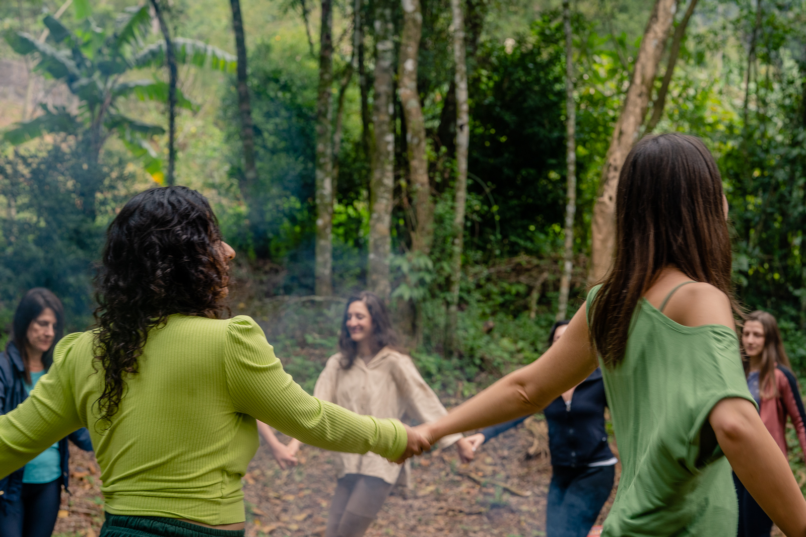 Mulheres em círculo na floresta, conectadas em ritual de acolhimento